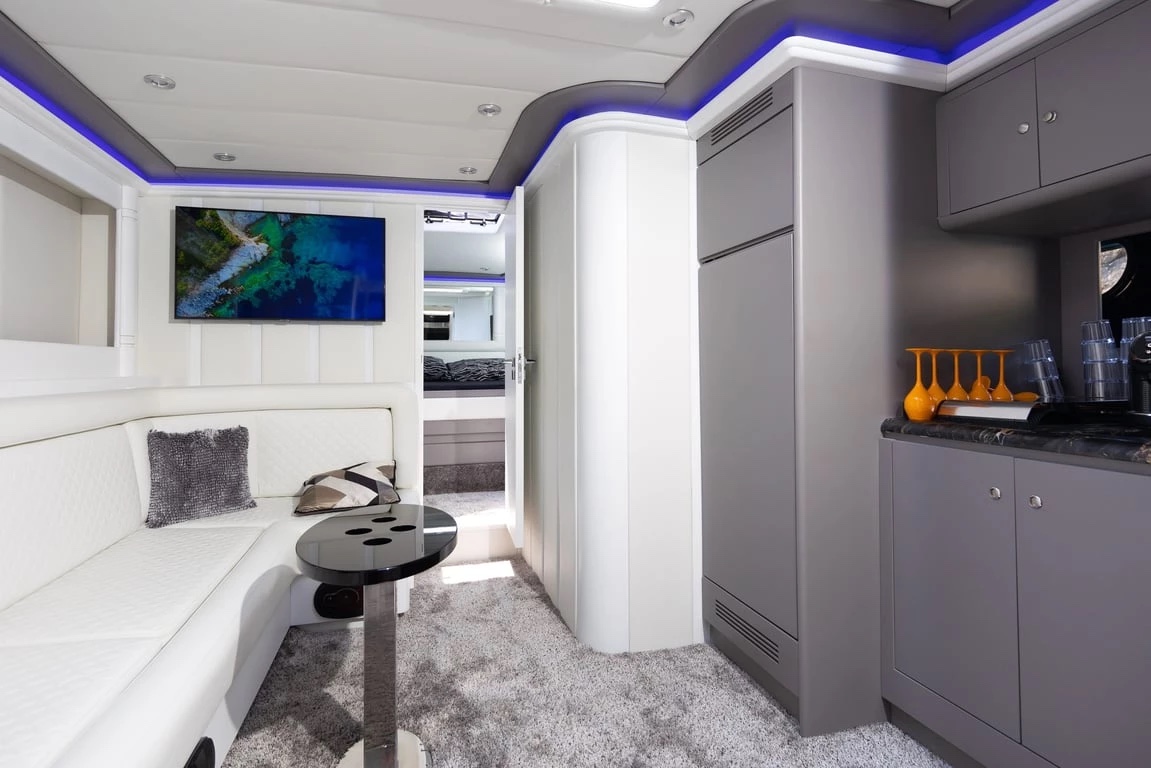 Air-conditioned saloon on Bond 007 with white leather seating, a wet bar and the aft cabin beyond