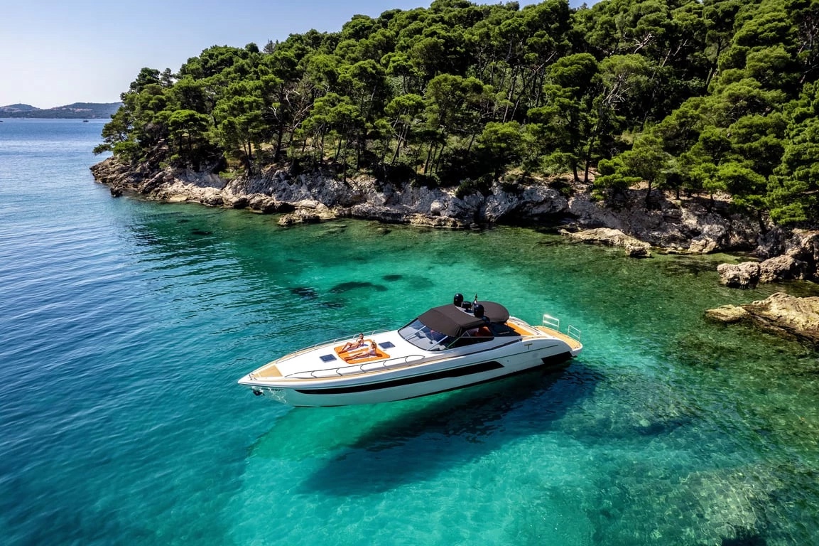 Bond 007 anchored in a turquoise pine-fringed cove, ready for a swim stop