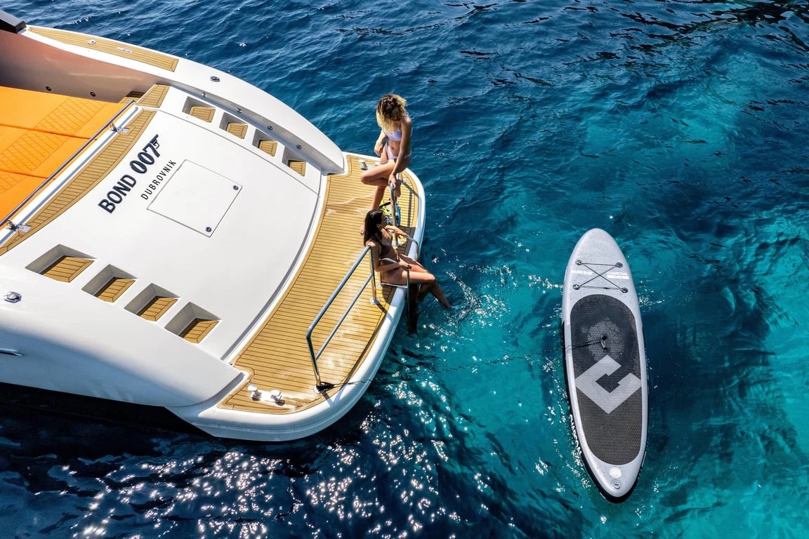Two guests on Bond 007's teak swim platform beside the stand-up paddleboard