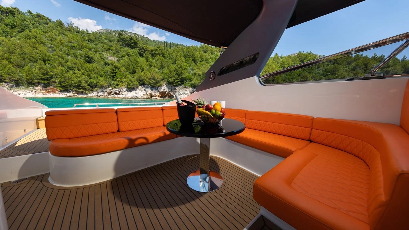 Shaded cockpit lounge on Bond 007 with orange quilted seating, fresh fruit and a champagne bucket