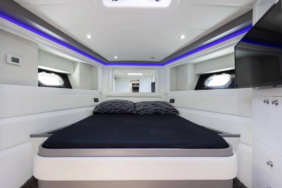 Master cabin on Bond 007 with a double bed, blue LED trim, twin portholes and a flat-screen TV