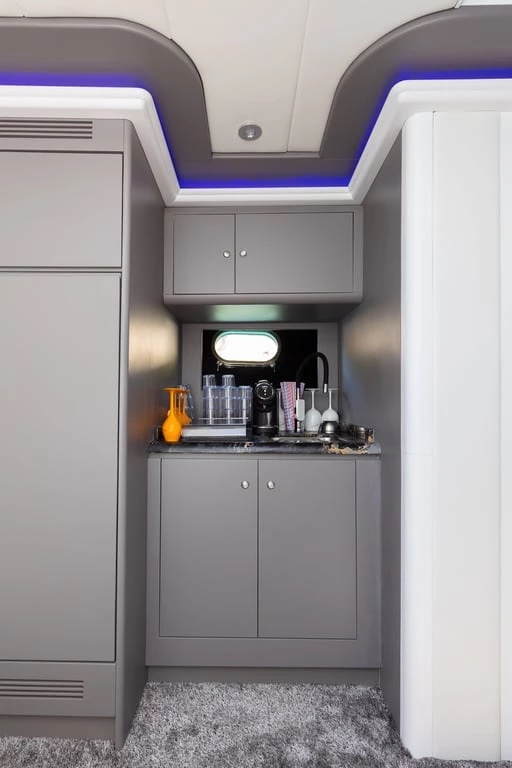 Galley corner on Bond 007 with a coffee machine, glassware and grey cabinetry