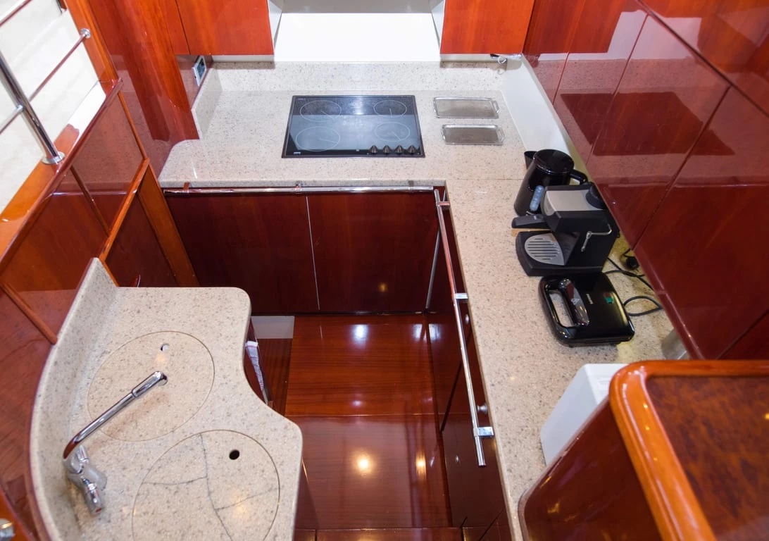 Galley on the Malavi 55 with four-ring hob, sink, coffee machine and glossy wood cabinetry