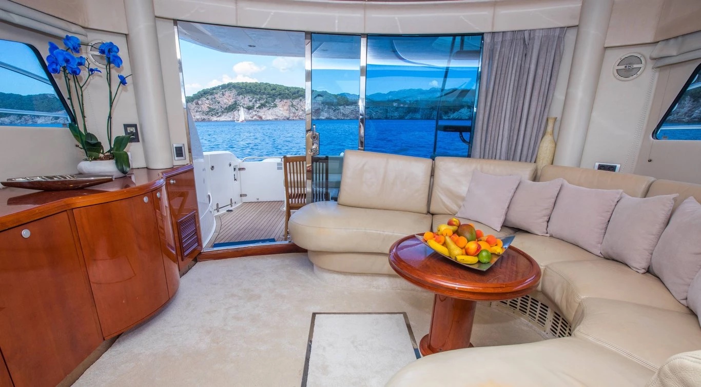 Saloon of the Malavi 55 with curved leather sofa, cherry-wood cabinetry and a view aft to the cockpit