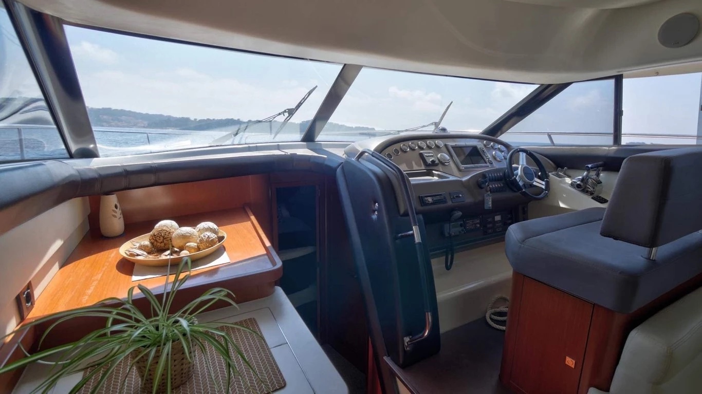 Lower helm and forward dinette inside the Prestige 440 Fly saloon, with sea views through the wraparound windscreen