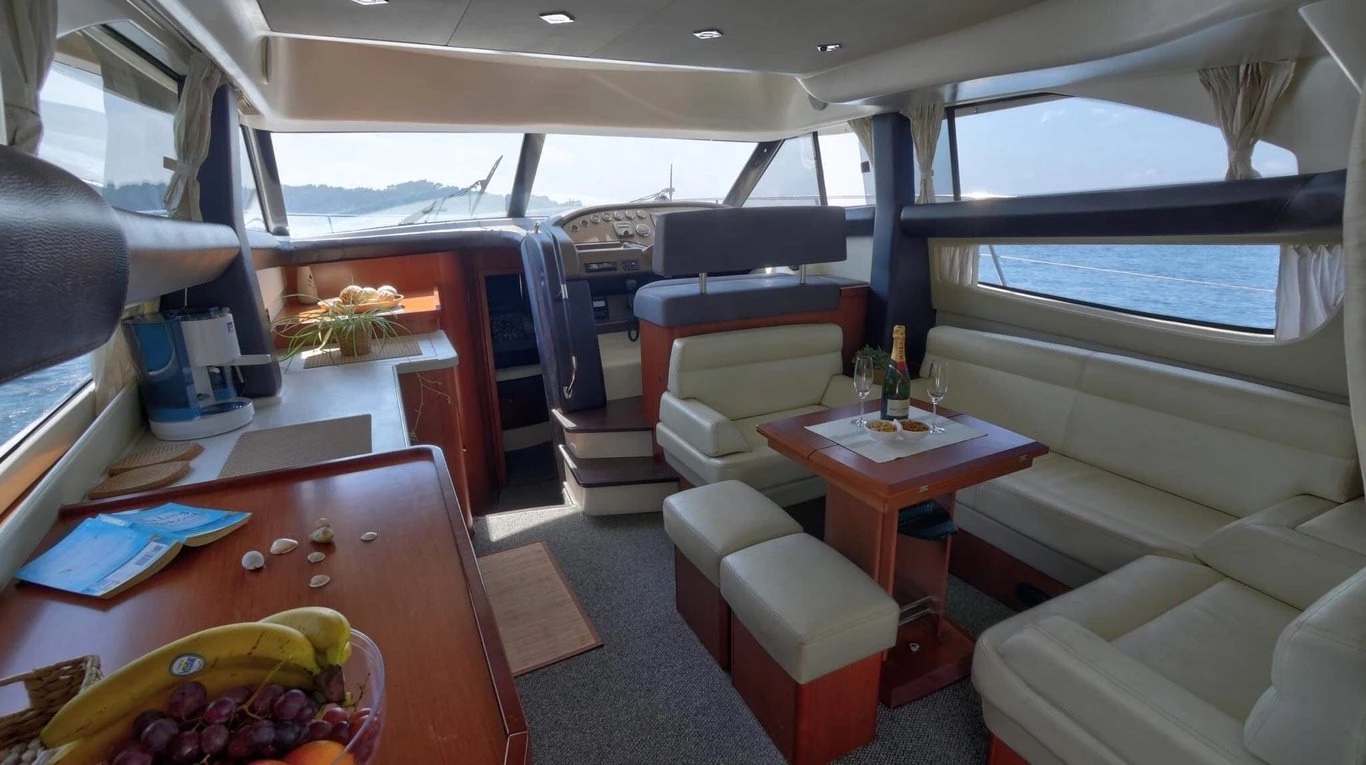 Saloon of the Prestige 440 Fly with cream leather seating, champagne on the table and the galley counter to port